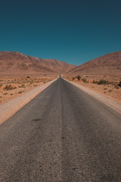 Vertical shot of a road in the middle of the desert and mountains captured in Morocco