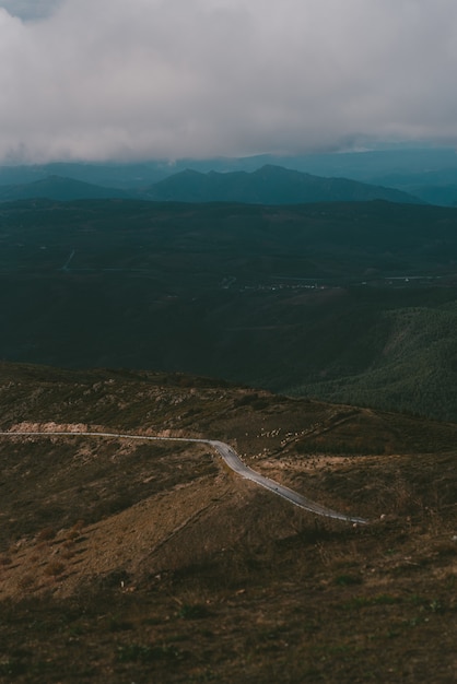 Vertical shot of a road up to the mountain under a cloudy sky