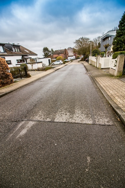 曇りの青い空と両側に家がある道路の垂直ショット