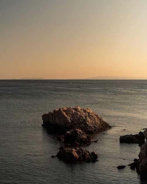 Vertical shot of rocks of different sizes in the sea under the clear sky