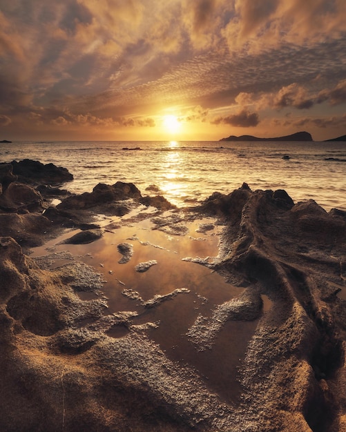 日の出時の岩の多いビーチと海の垂直ショット