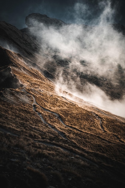 Free photo vertical shot of rocky mountains covered with clouds