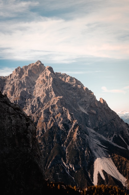 이탈리아 돌로미티 산맥(Dolomites Mountain Range)에 햇볕이 잘 드는 봉우리가 있는 험준한 바위 산의 수직 샷