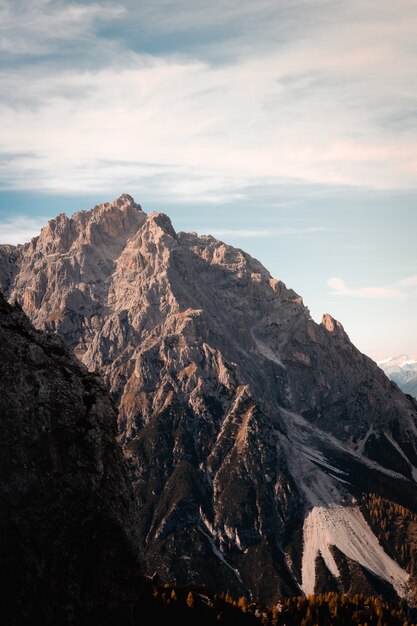 이탈리아 돌로미티 산맥(Dolomites Mountain Range)에 햇볕이 잘 드는 봉우리가 있는 험준한 바위 산의 수직 샷