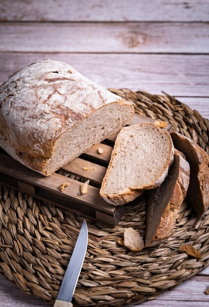 Vertical shot of rustic village bread cut in slices on the wooden board