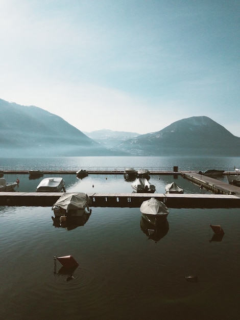 Vertical shot of sailboats on the body of water with high mountains