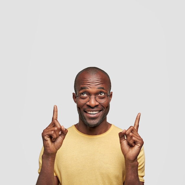 Vertical shot of satisfied middle aged man points upwards