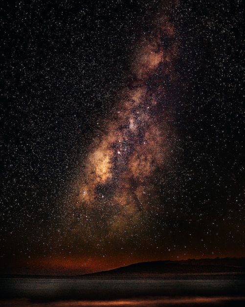 Vertical shot of a sea under a starry sky with milky way