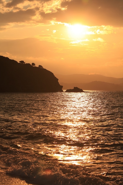 Vertical shot of the sea surrounded by mountains during sunset