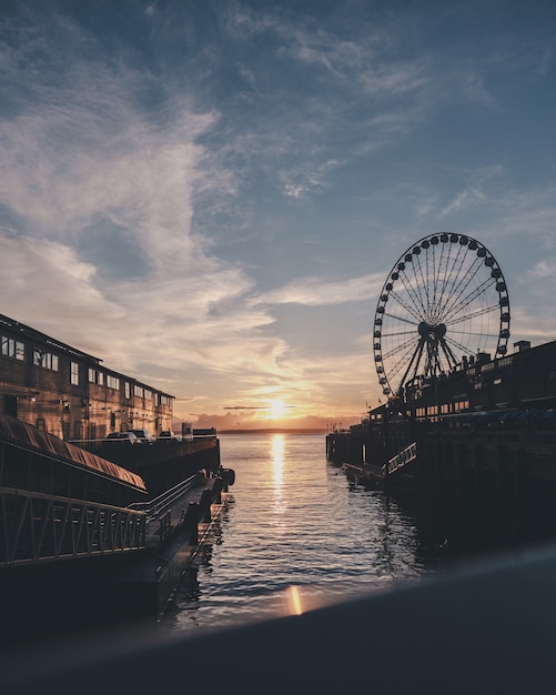 Vertical shot of the sea with a ferries wheel in the distance under a blue sky