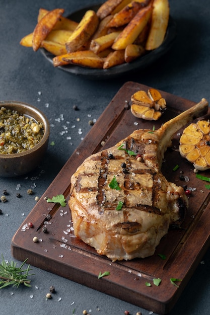 Vertical shot of a seasoned stake on a board served with fries