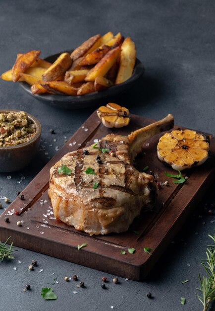 Vertical shot of a seasoned stake on a board served with fries