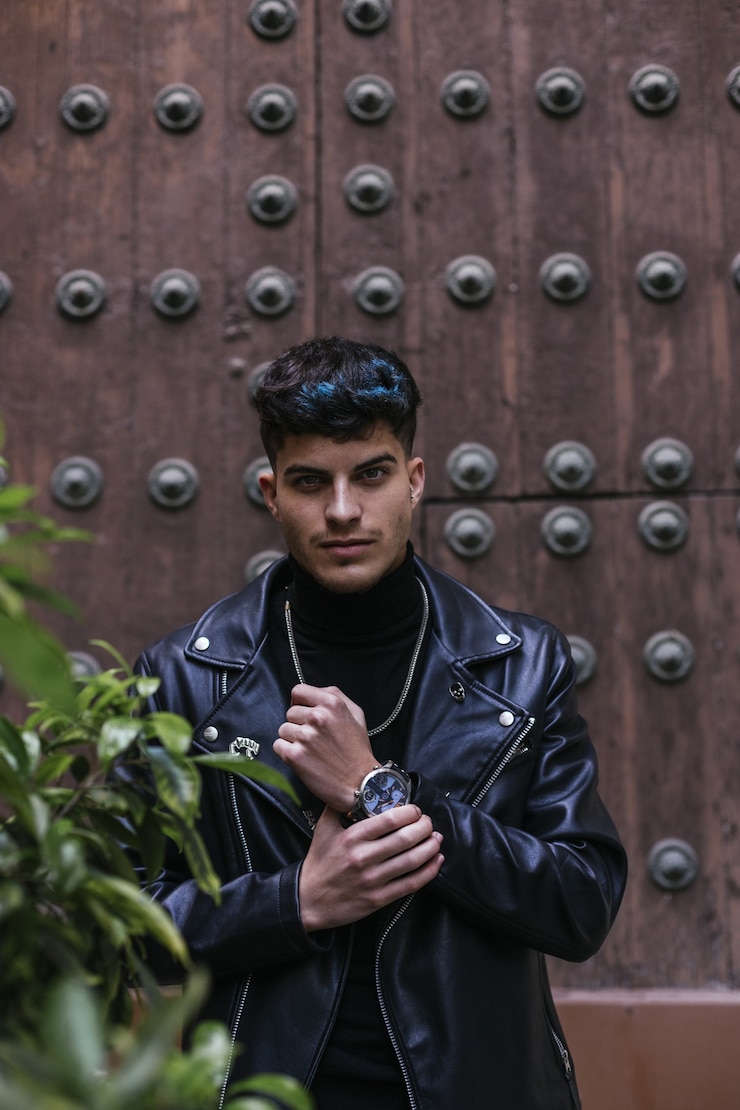 Free Photo vertical shot of a serious young man wearing a turtleneck, leather jacket, necklace, and a watch