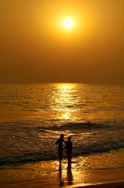 Vertical shot of a silhouette of a couple in the beach