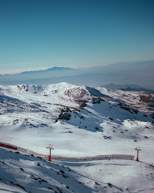 Вертикальный снимок горнолыжного курорта, покрытого снегом под солнечным светом и голубым небом
