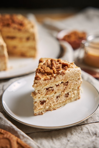 Vertical shot of a slice of delicious lotus cookie cake with caramel with cookies on the table