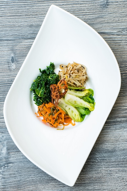 Free photo vertical shot of sliced vegetables and noodle on a white modern plate