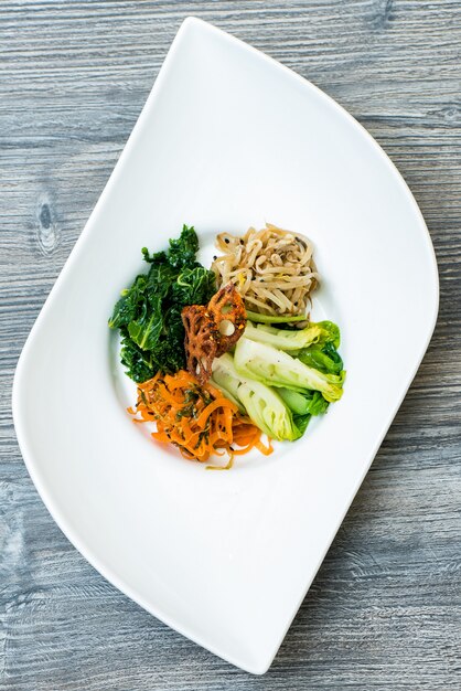 Vertical shot of sliced vegetables and noodle on a white modern plate