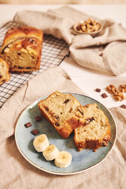 Vertical shot of slices of delicious banana bread with chocolate chunks and walnut on a plate