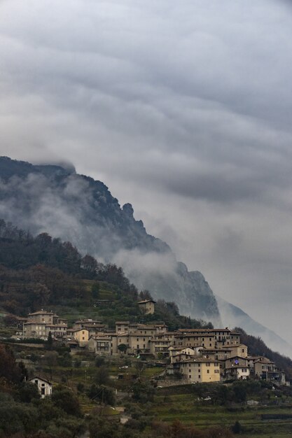 Vertical shot of a small Italian village on a mountain surrounded by fog