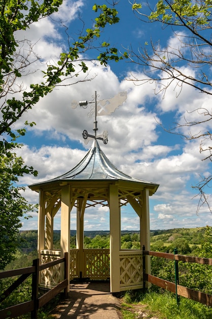 Free photo vertical shot of a small tower in front of a forest under a cloudy sky