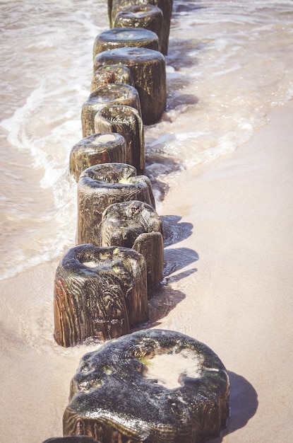 Foto gratuita colpo verticale di piccole assi di legno su una spiaggia sabbiosa