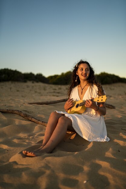 砂地に座っている白いドレスを着た笑顔の女性の垂直ショット