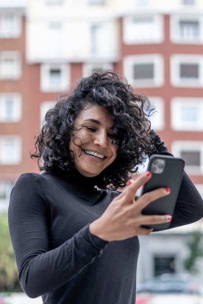 Ripresa verticale di una donna spagnola che sorride mentre usa il telefono