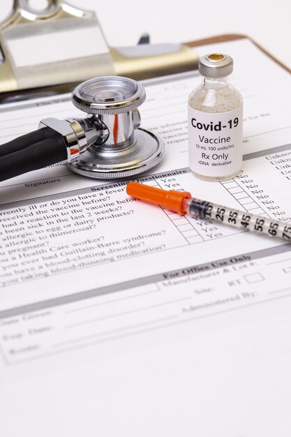 Vertical shot of a stethoscope, medicine, and syringe on a printed paper