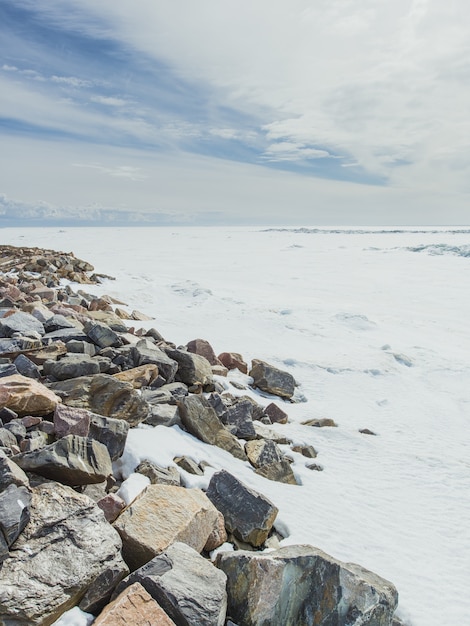 Vertical shot of the stones near the valley covered with snow in winter under the cloudy sky