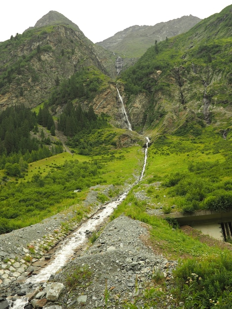 Vertical shot of a stream flowing water with green mountains