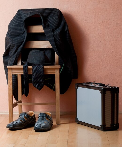 Vertical shot of a suit on the chair next to shoes and a briefcase