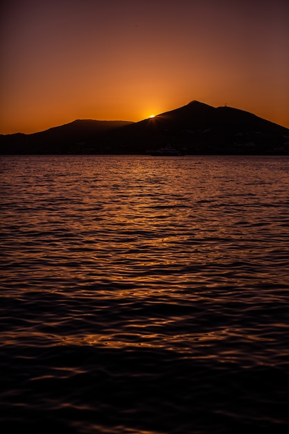 ギリシャ、ナクソスの山の後ろに沈む夕日の垂直ショット