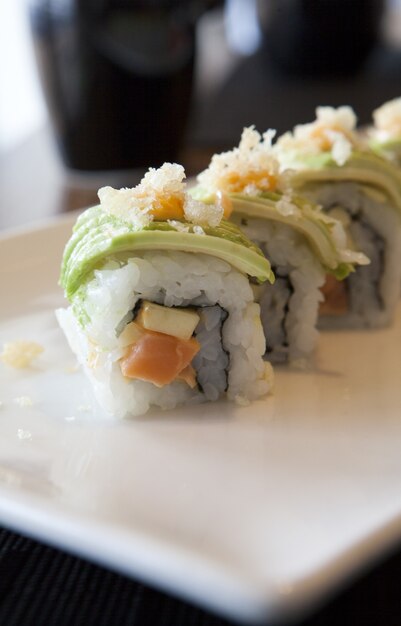 Вертикальный снимок суши-роллов на тарелке на столе