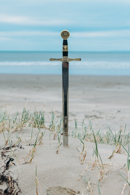 Vertical shot of a sword in the sandy beach