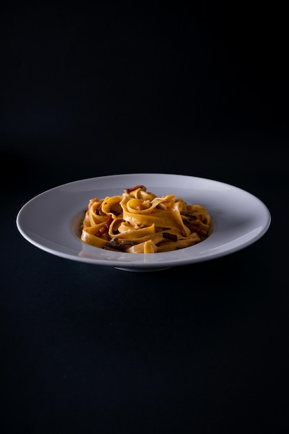 Vertical shot of a tagliatelle bolognese on black background