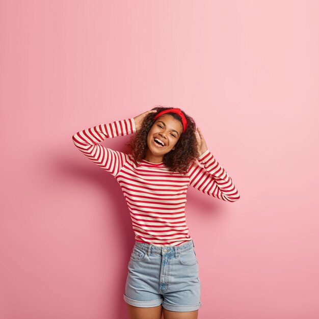 Vertical shot of teenage girl with curly hair posing in striped red sweater