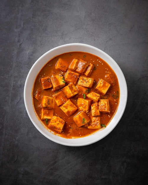 Traditional Indian Paneer Butter Masala or Cheese Cottage Curry on a Black Surface