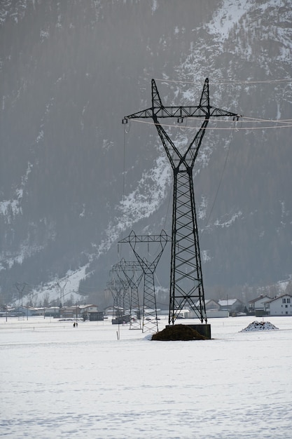 Foto gratuita colpo verticale di una torre di trasmissione con una superficie innevata durante l'inverno