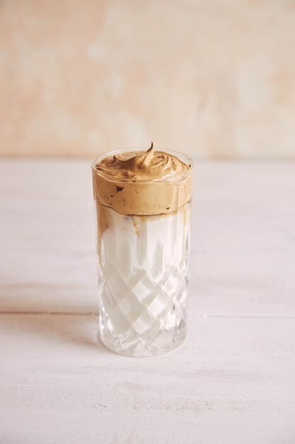 Vertical shot of a trendy delicious fresh Dalgona coffee with milk on a white wood table