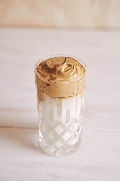 Vertical shot of a trendy delicious fresh Dalgona coffee with milk on a white wood table