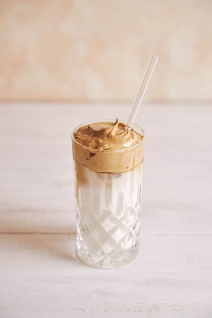 Vertical shot of a trendy delicious fresh Dalgona coffee with milk on a white wood table