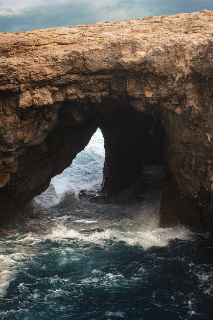 Vertical shot of the waters of the ocean under a cliff