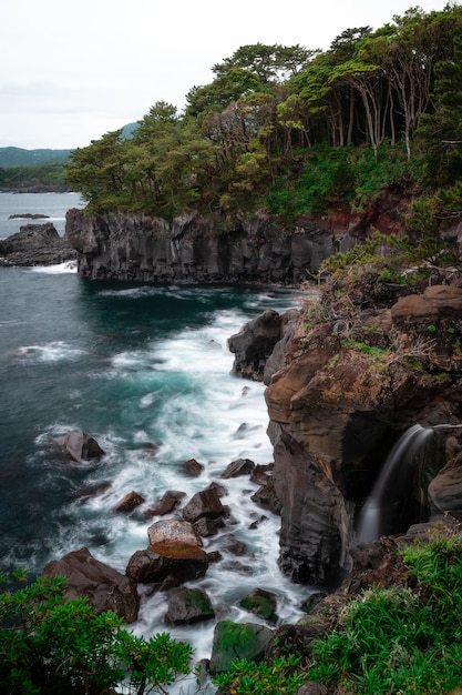 Free photo vertical shot of the waves of the sea crashing on the cliffs