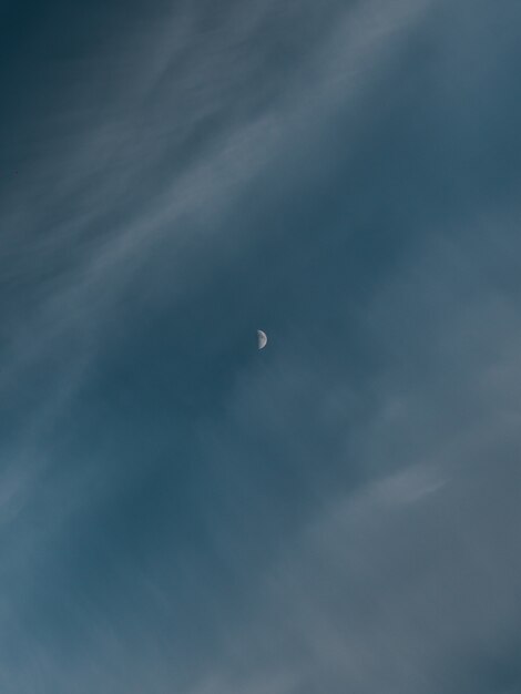 Vertical shot of a waxing crescent moon behind the clouds