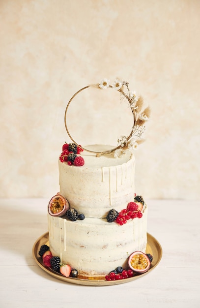 Vertical shot of a wedding cake decorated with fresh fruits and berries and a flower ring