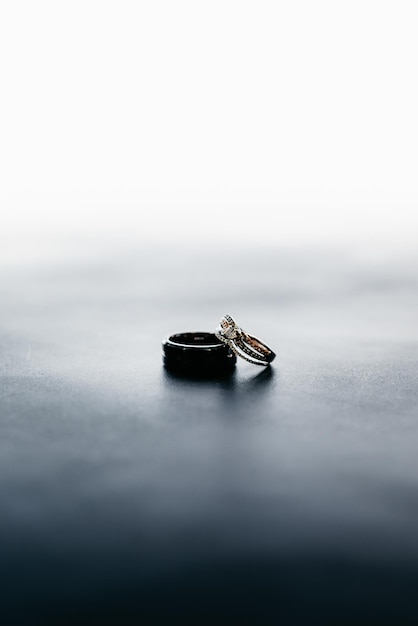 Free photo vertical shot of wedding rings of bride and groom on a gray surface