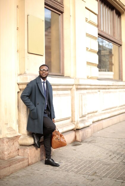 Vertical shot of a well-dressed male leaning on a wall