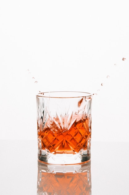 Вертикальный снимок бокала виски, отражающегося на столе