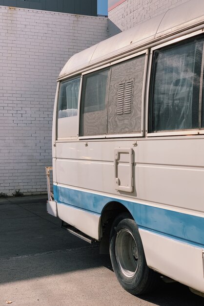 Vertical shot of a white and blue van parked outside during daytime